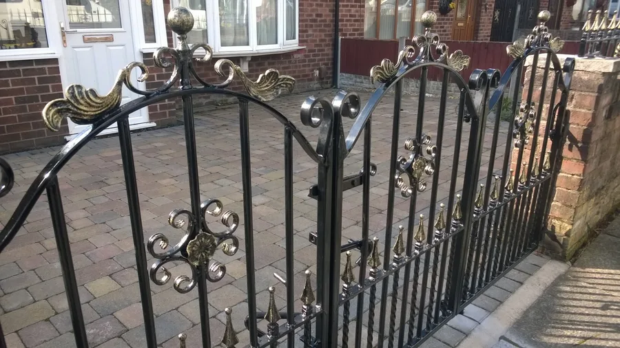Arched wrought iron gates with ornate scrollwork and gold-coloured details